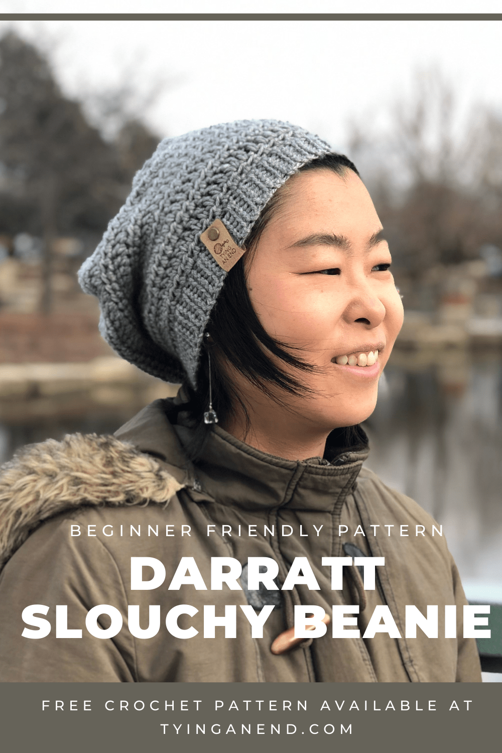 woman wearing gray crochet slouchy beanie in front of a pond, smiling