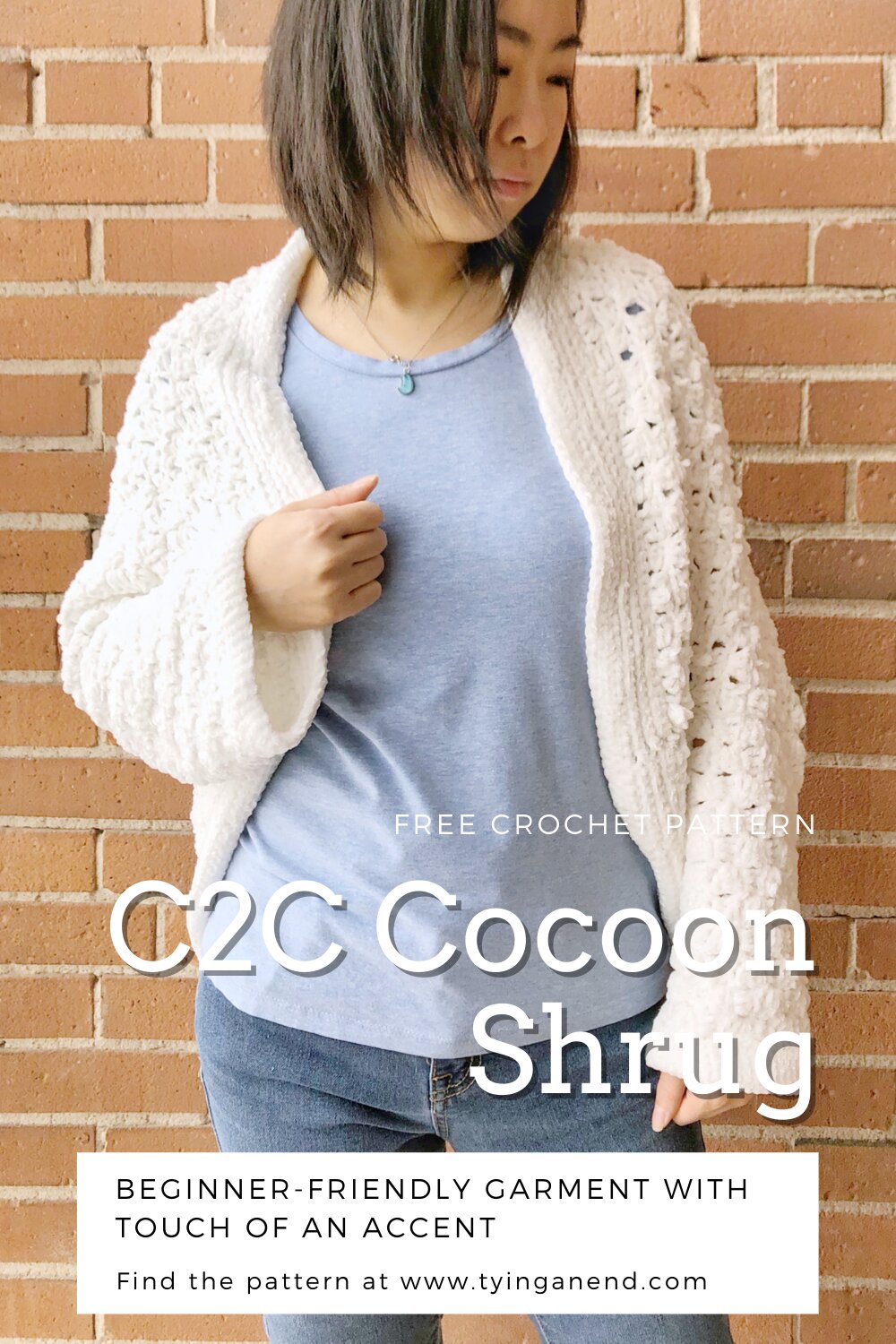 woman wearing white crochet c2c cocoon shrug in front of a brick wall